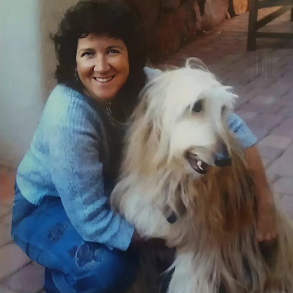 Kate McGahan: Portrait of a woman with her Afghan Hound. A smiling woman lovingly holds a fluffy white Afghan Hound dog.
