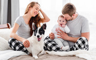 Happy family in pajamas with baby and dog on bed