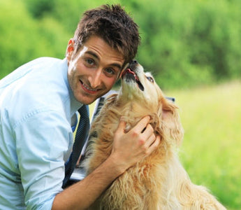 Happy man hugging his golden retriever dog outdoors.