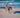 Brown dog running on beach with ball, supporting active performance.