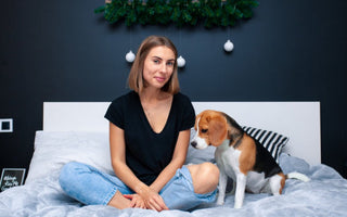 Woman sits on bed with Beagle dog.  Christmas decor in background.