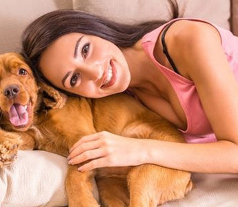 Happy woman cuddling her Cocker Spaniel dog on a couch
