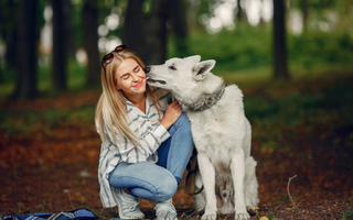 Woman cuddling her white Swiss Shepherd dog in a forest