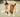 Two Golden Retrievers sitting on a paved path, one yawning