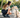 Young woman crouching, giving treat to golden retriever puppy in park.