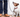Jack Russell Terrier dog sits patiently on a leash, looking up at its owner.