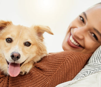 Happy woman cuddling her fluffy golden dog on a couch.