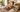 Dog relaxing on a brown PEMF mat on a bed with a woman nearby.