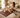 Dog relaxing on a brown PEMF mat on a bed with a woman nearby.