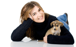 Happy woman cuddling a small brown and white puppy