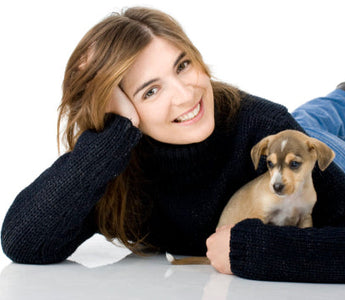 Happy woman cuddling a small brown and white puppy