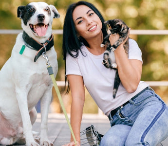 Happy woman with her dog and kitten outdoors