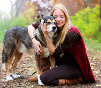 Woman hugs her mixed-breed dog in an autumn forest.
