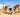 Two dogs playfully digging in the sand at the beach.