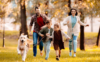 Happy family with kids and dog running in autumn park