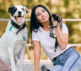 Happy woman with her dog and cat outdoors