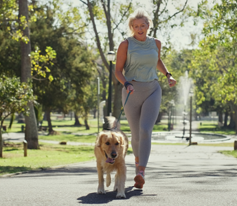 Woman jogging with golden retriever in park