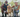 Happy senior couple squatting with their Golden Retriever dog in a park.