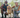 Happy senior couple squatting with their Golden Retriever dog in a park.