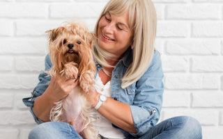Happy senior woman cuddling her Yorkshire Terrier dog.
