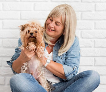 Happy senior woman cuddling her Yorkshire Terrier dog.