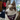 A close-up of a brown and white Siberian husky wearing a red and navy plaid bandana with the white text 'I CAN EXPLAIN' and a paw print, in a bedroom setting.